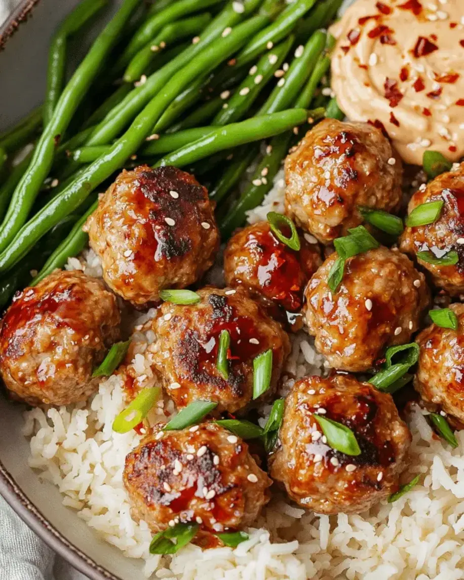 Juicy firecracker meatballs sizzling in a pan, ready to meld with coconut rice and green beans.