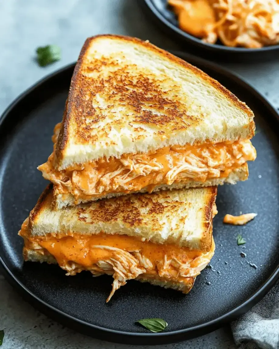 Close-up of crispy grilled buffalo chicken sandwich with dripping cheese and fresh garnish
