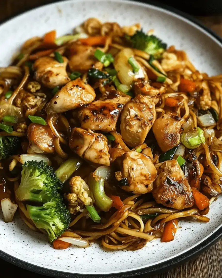 Plated Garlic Chicken Lo Mein with sautéed vegetables, garnished and ready to eat