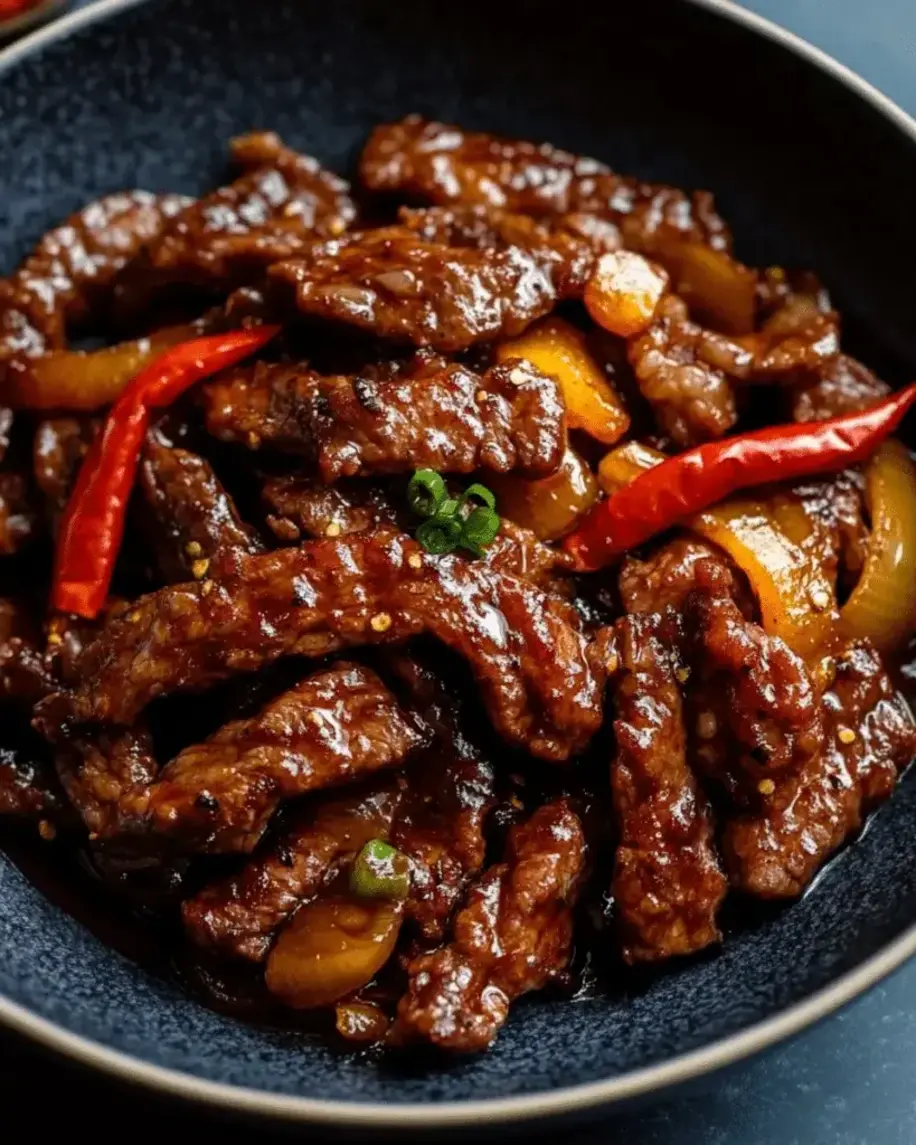 Finished dish of Crispy Stir-Fried Sirloin Steak with Sweet Chili Sauce, served sizzling hot on a plate