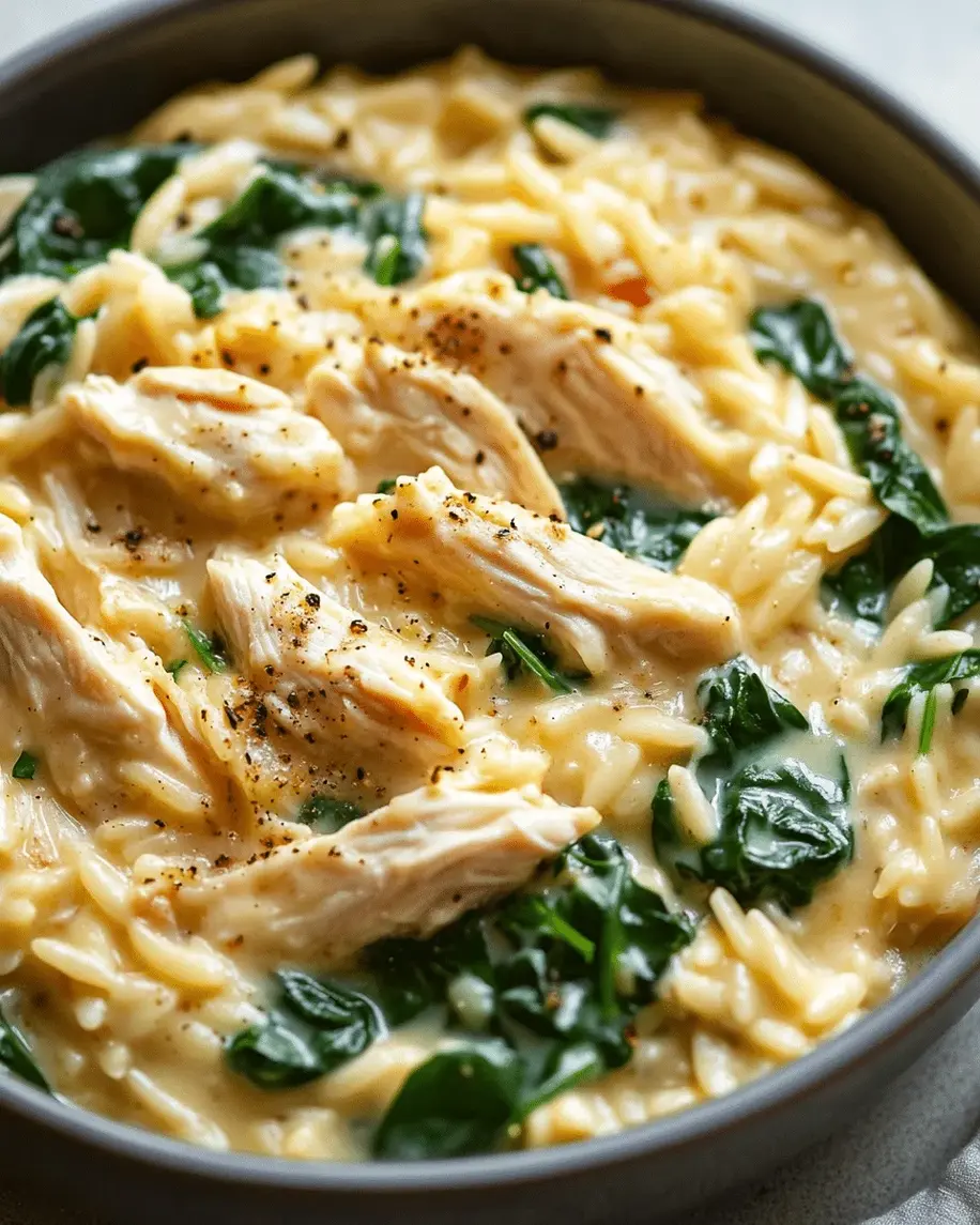 A vibrant close-up of creamy orzo mixed with chicken pieces and wilted spinach in a simmering pot, showcasing the rich, creamy texture and fresh ingredients.