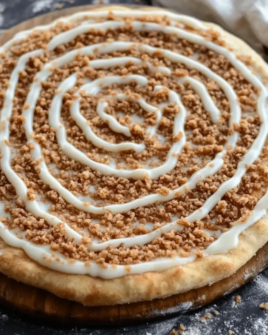 Close-up view of sliced easy homemade cinnamon crumb dessert pizza with fresh icing drizzle