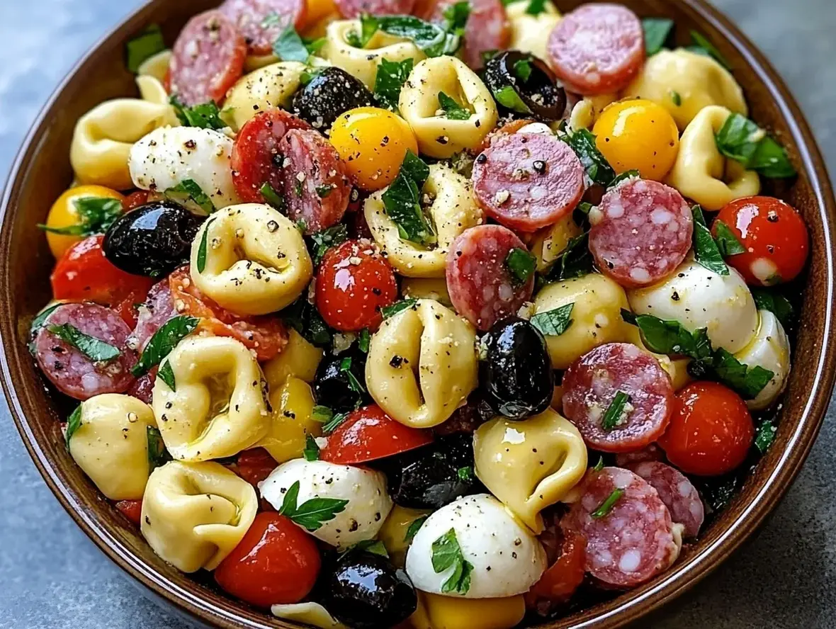 A vibrant tortellini pasta salad with cherry tomatoes, cucumber, and olives.