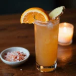 Cortisol balancing mocktail recipe in amber glass on dark walnut wood with orange slice and ginger
