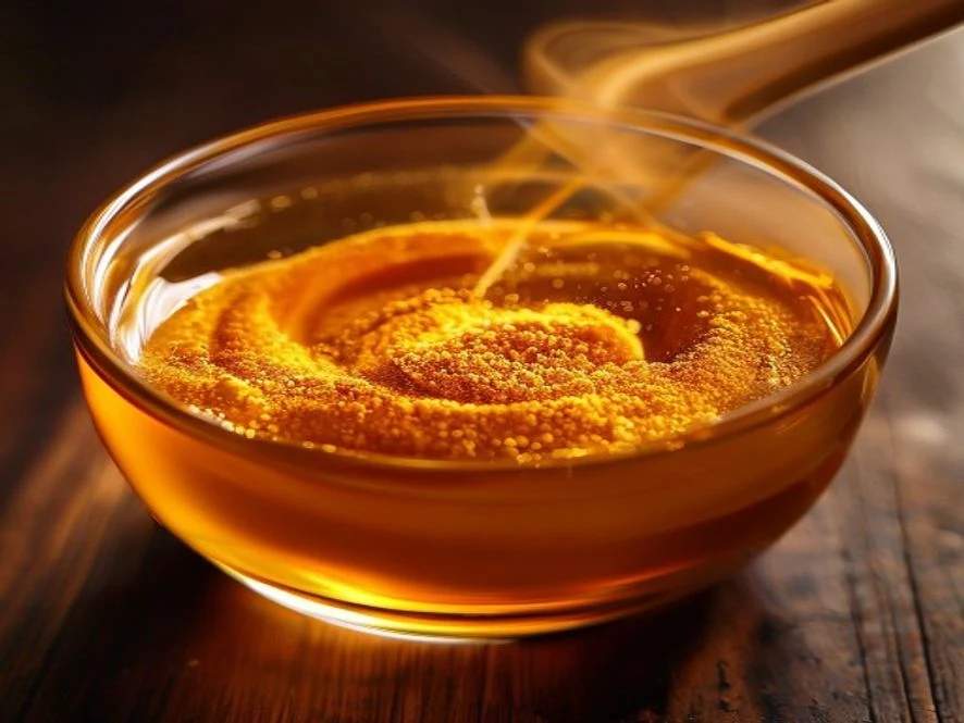 Ashwagandha powder being stirred into amber cortisol mocktail drink in glass with wooden stirrer