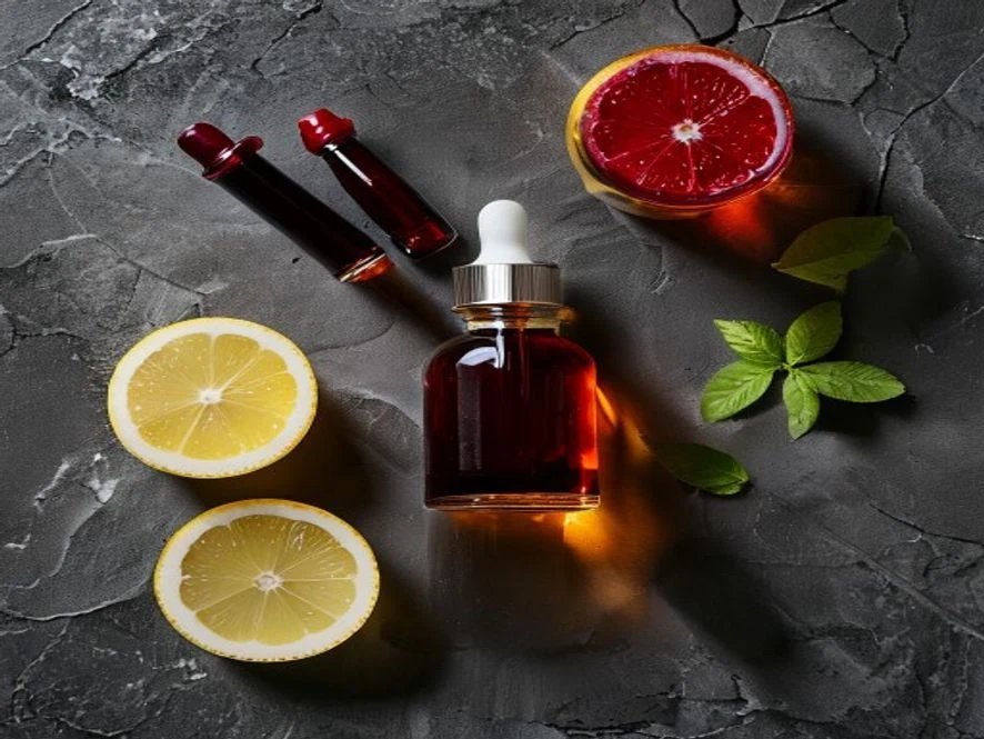 Flat-lay of liquid magnesium sleep mocktail ingredients including amber dropper bottle, tart cherry juice, sparkling water, lemon and honey on dark slate
