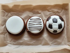 Drawing black pentagon soccer ball lines on a white-coated Little Debbie brownie using a black gel icing pen