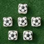 Little Debbie soccer brownies decorated with white candy melt coating and black gel icing soccer ball lines on a green surface