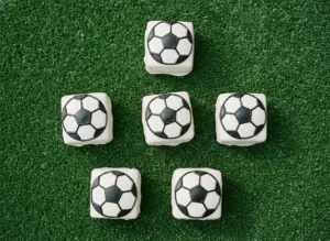 Little Debbie soccer brownies decorated with white candy melt coating and black gel icing soccer ball lines on a green surface