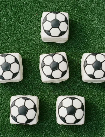 Little Debbie soccer brownies decorated with white candy melt coating and black gel icing soccer ball lines on a green surface