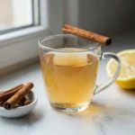 glucose reset ritual recipe in a clear glass mug with cinnamon and lemon on marble counter
