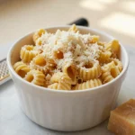 Pastina dot cake recipe — creamy stelline pastina in a white paper cup heaped with freshly grated parmesan on a marble counter